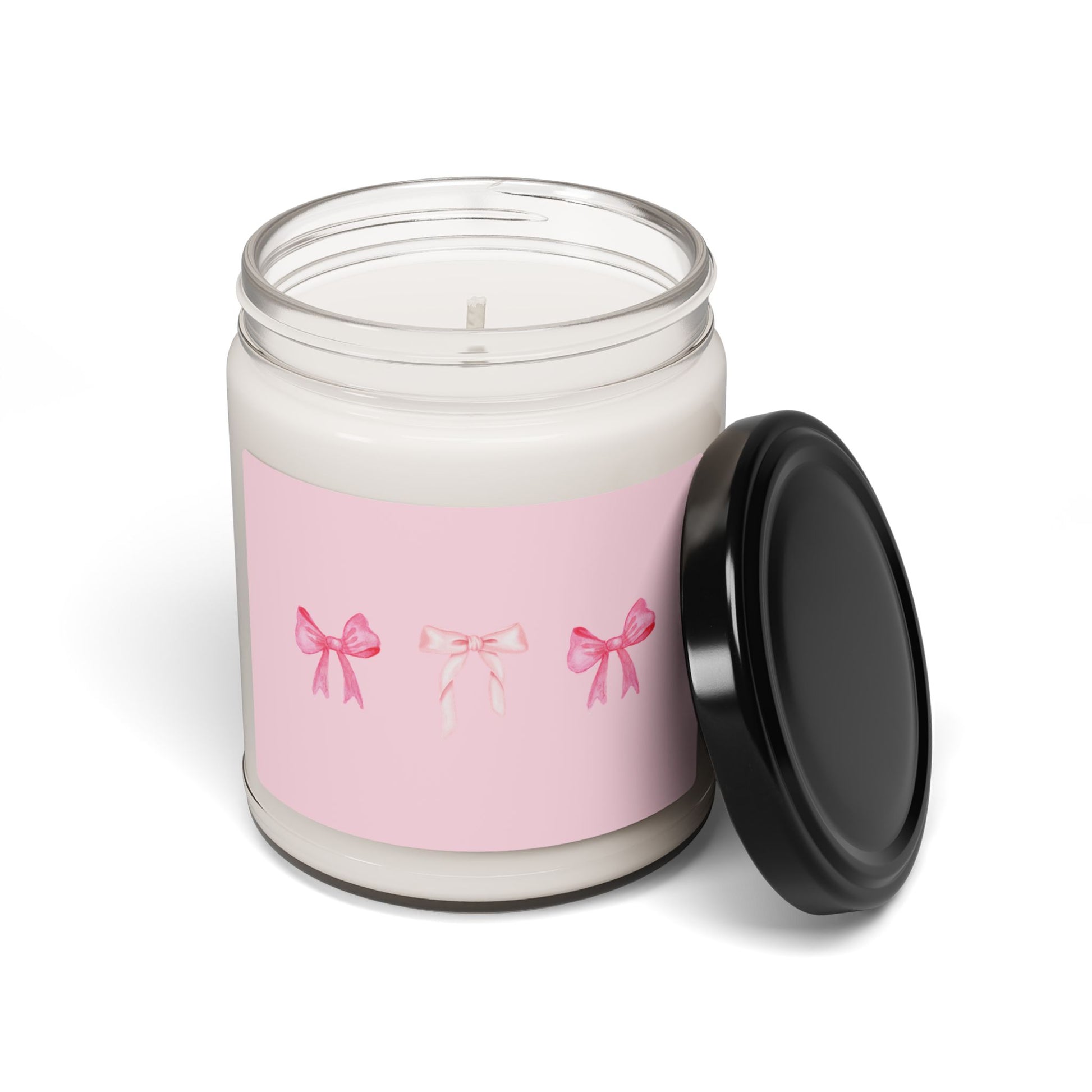 Candle jar with pink label featuring bows and black lid on a white background