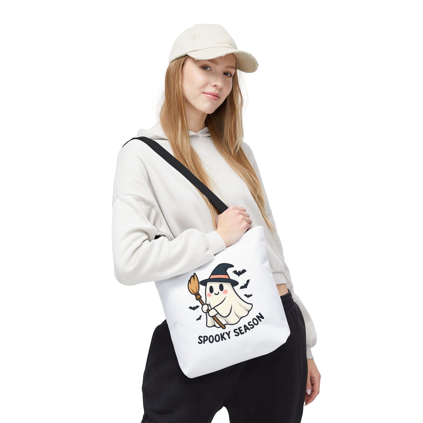 Person wearing a white cap and holding a white bag with a ghost design and 'Spooky Season' text.