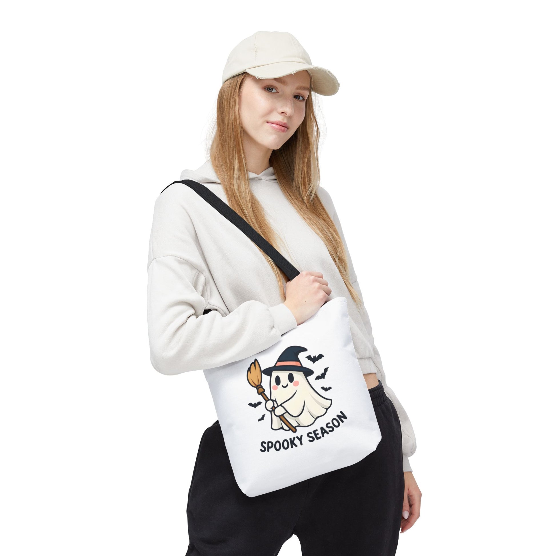 Person wearing a white cap and holding a white bag with a ghost design and 'Spooky Season' text.